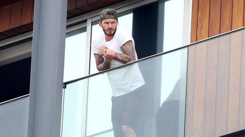 David Beckham aparece na sacada do hotel onde está hospedado, no Rio