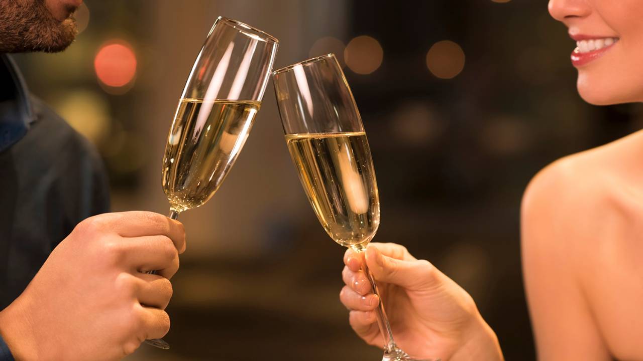 Casal brindando com champagne, em restaurante