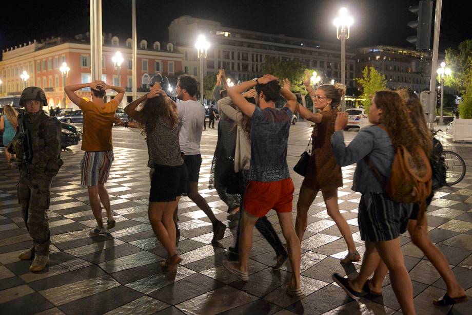 Pedestres caminham com as mãos na cabeça, durante patrulha de soldados, após caminhão atropelar multidão em Nice, na França - 14/07/2016