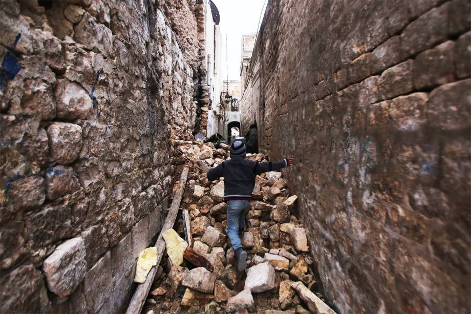 Garoto sírio caminha entre prédios destruídos, no bairro de Dahret Awad, em Alepo, durante a evacuação de áreas rebeldes do local - 17/12/2016