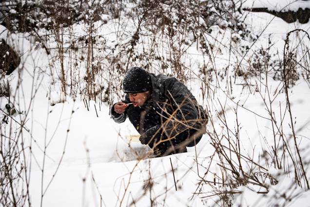 Migrante se alimenta sentado na neve em Belgrado, na Sérvia - 11/01/2017 Migrante se alimenta sentado na neve em Belgrado, na Sérvia - 11/01/2017