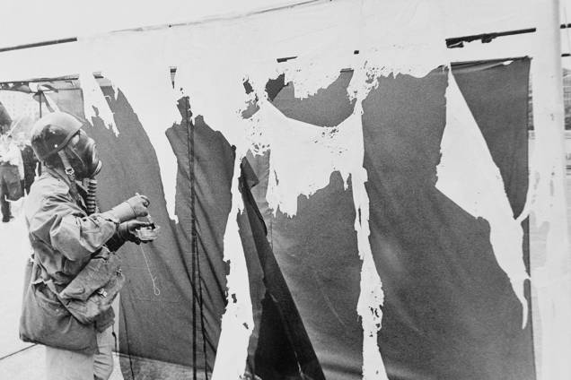 O artista alemão Gustav Metzger veste uma máscara de gás enquanto pinta cortinas de nylon com ácido clorídrico, fazendo com que se desintegram, em 1961 O artista alemão Gustav Metzger veste uma máscara de gás enquanto pinta cortinas de nylon com ácido clorídrico, fazendo com que se desintegram, em 1961