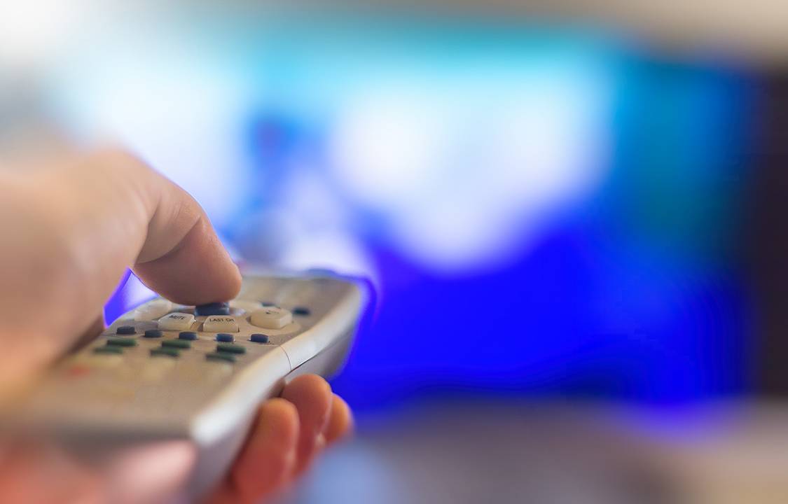 Close up of remote in hand with shallow depth of field during television watching