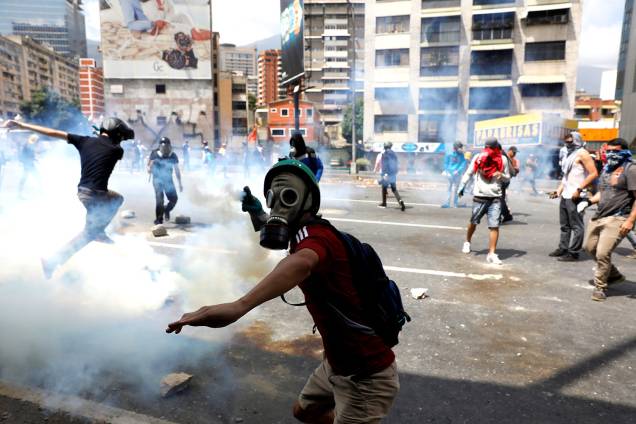Manifestante joga gás lacrimogêneo de volta aos policiais durante o protesto em Caracas, Venezuela, contra o governo de Nicolás Maduro - 06/04/2017 Manifestante joga gás lacrimogêneo de volta aos policiais durante o protesto em Caracas, Venezuela, contra o governo de Nicolás Maduro - 06/04/2017