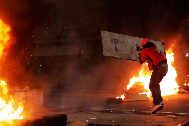 Integrante do Movimento dos Trabalhadores Sem-Teto lança um tábua de madeira sobre uma barricada em chamas durante protesto contra as reformas do governo Michel Temer em São Paulo - 28/04/2017 Integrante do Movimento dos Trabalhadores Sem-Teto lança um tábua de madeira sobre uma barricada em chamas durante protesto contra as reformas do governo Michel Temer em São Paulo - 28/04/2017