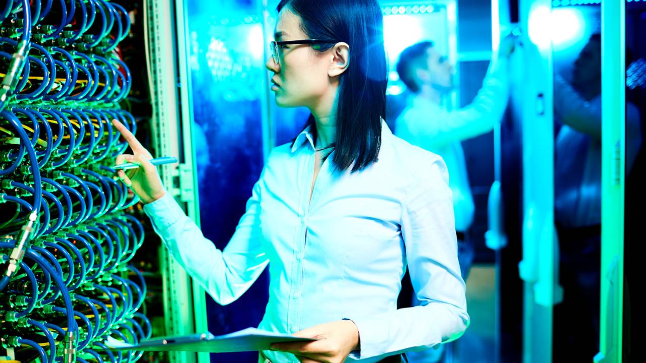 Mulher em sala de servidores - Profissional de tecnologia - Computadores