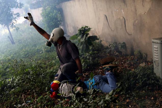 Manifestante ferido é ajudado por outro após confronto com a polícia durante a chamada 'mãe de todas as marchas' contra o presidente da Venezuela, Nicolás Maduro, em Caracas - 19/04/2017 Manifestante ferido é ajudado por outro após confronto com a polícia durante a chamada 'mãe de todas as marchas' contra o presidente da Venezuela, Nicolás Maduro, em Caracas - 19/04/2017