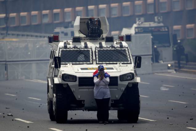 Manifestante de oposição bloqueia a passagem de um carro blindado durante protesto contra o presidente Nicolás Maduro em Caracas - 19/04/2017 Manifestante de oposição bloqueia a passagem de um carro blindado durante protesto contra o presidente Nicolás Maduro em Caracas - 19/04/2017