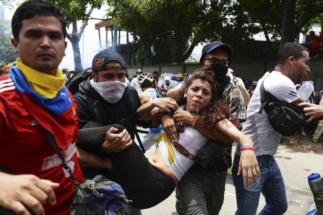 Mulher atingida por gás lacrimogêneo disparado pela polícia é carregada por outros manifestantes durante uma marcha contra o presidente venezuelano, Nicolás Maduro, em Caracas - 19/04/2017 Mulher atingida por gás lacrimogêneo disparado pela polícia é carregada por outros manifestantes durante uma marcha contra o presidente venezuelano, Nicolás Maduro, em Caracas - 19/04/2017