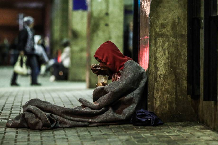 Morador de rua se alimenta com sopa distribuída por voluntários, na região central de São Paulo