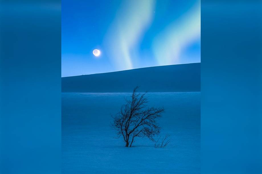 Lua crescente e Marte fotografados sobre o solo coberto de neve da cordilheira de <span>Saltfjellet, na Noruega. A aurora boreal apareceu de surpresa na imagem, segundo o fotógrafo.</span>