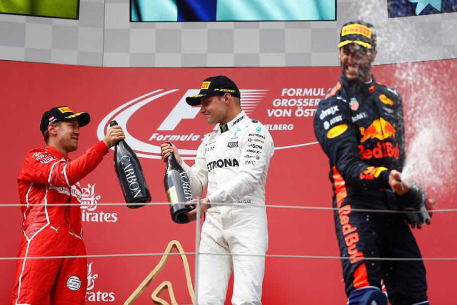 O finlandês Valtteri Bottas, da Mercedes, comemora no pódio com Sebastian Vettel, da Ferrari, e Daniel Ricciardo, da Red Bull Racing, após vencer o GP da Áustria