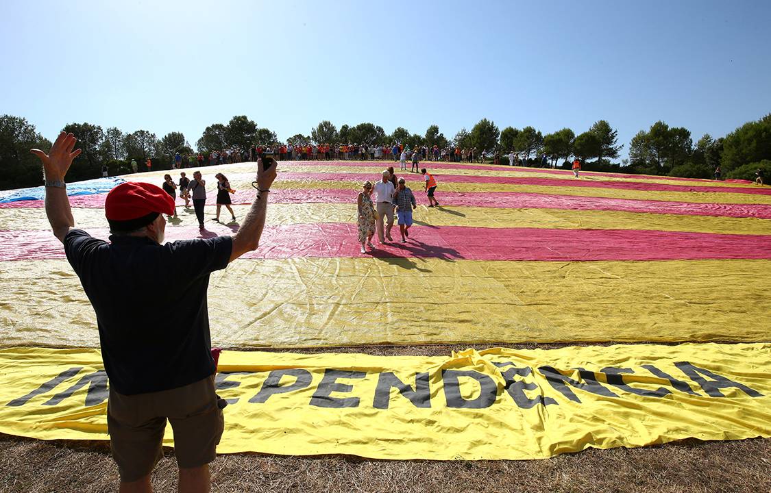Homem comemora o movimento separatista da Catalunha com bandeira estendida em Barcelona, Espanha