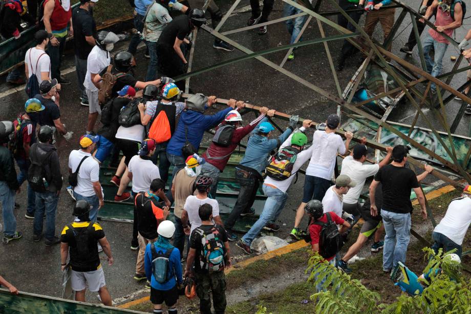 Manifestantes de oposição arrastam uma estrutura metálica para montar uma barricada durante confronto com a polícia em Caracas, na Venezuela - 30/07/2017