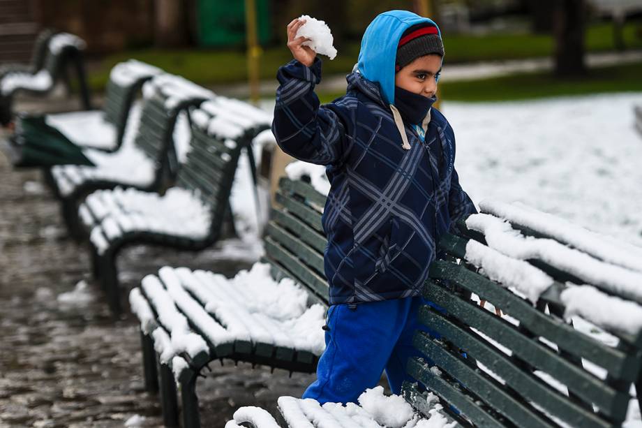 Criança atira bola de neve enquanto brinca em uma praça no centro de Santiago, após uma nevasca inesperada atingir a cidade, no Chile - 15/07/2017