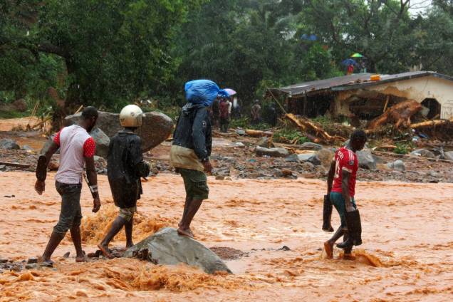 Moradores atravessam uma rua inundada em frente a uma casa em destruída pelas enchentes em Freetown, capital de Serra Leoa - 14/08/2017 Moradores atravessam uma rua inundada em frente a uma casa em destruída pelas enchentes em Freetown, capital de Serra Leoa - 14/08/2017