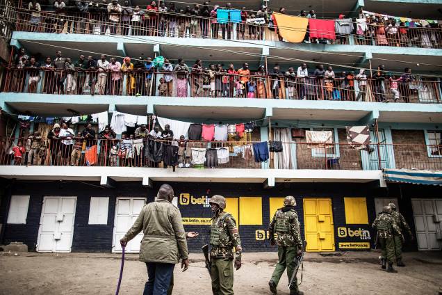 Moradores observam das sacadas enquanto policiais administrativos do Quênia patrulham a região da favela de Mathare, em Nairobi, durante o protesto contra o resultado das eleições gerais Moradores observam das sacadas enquanto policiais administrativos do Quênia patrulham a região da favela de Mathare, em Nairobi, durante o protesto contra o resultado das eleições gerais