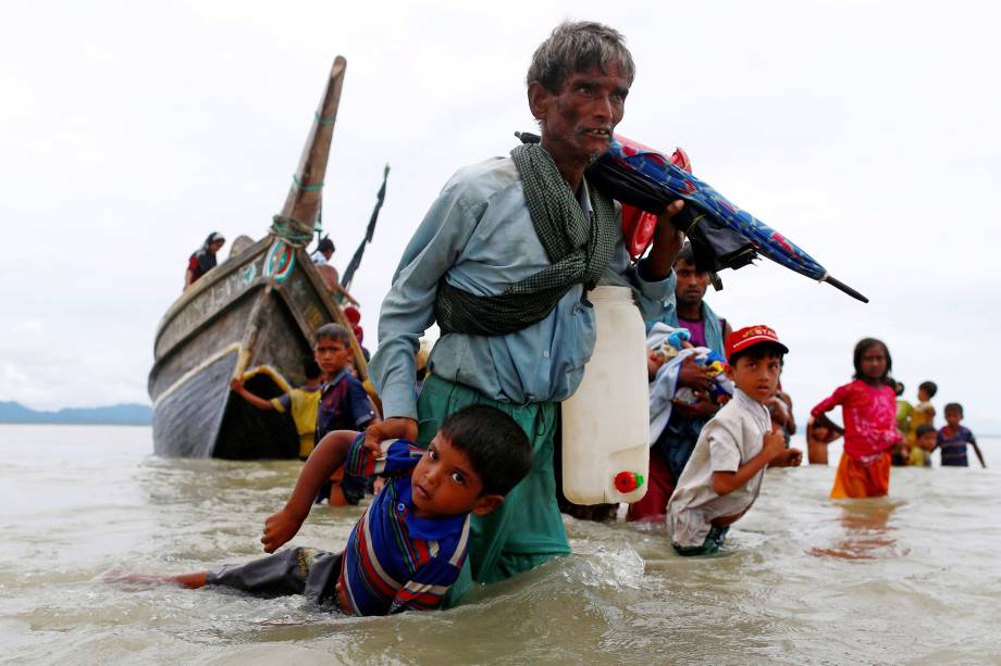 Refugiado rohingya carrega uma criança  até a costa após atravessar a fronteira entre Bangladesh e Myanmar de barco pela Baía de Bengala em Shah Porir Dwip, no Bangladesh - 10/09/2017