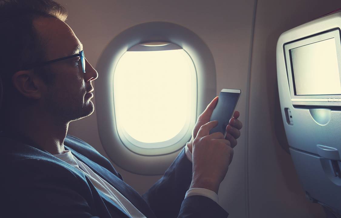 Homem usando smartphone em avião