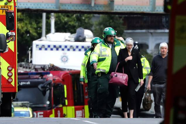 Uma mulher e um homem feridos na explosão de uma bomba caseira no metrô são conduzidos pela equipe de emergência, para fora da estação de Parsons Green, em Londres - 15/09/2017 Uma mulher e um homem feridos na explosão de uma bomba caseira no metrô são conduzidos pela equipe de emergência, para fora da estação de Parsons Green, em Londres - 15/09/2017