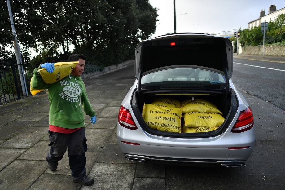 Um homem carrega seu carro com sacos de areia para proteger as casas na costa da baía de Dublin durante a passagem da tempestade Ophelia pela Irlanda - 16/10/2017