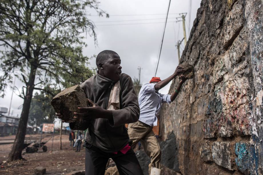 Manifestantes de oposição ao presidente do Quênia usam pedras para destruir uma parede na favela de Kibera, em Nairóbi durante protestos contra as eleições - 26/10/2017