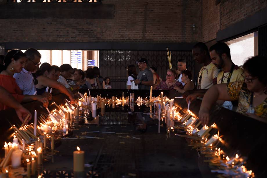 Fiéis acendem vela durante a véspera do dia de Nossa Senhora Aparecida