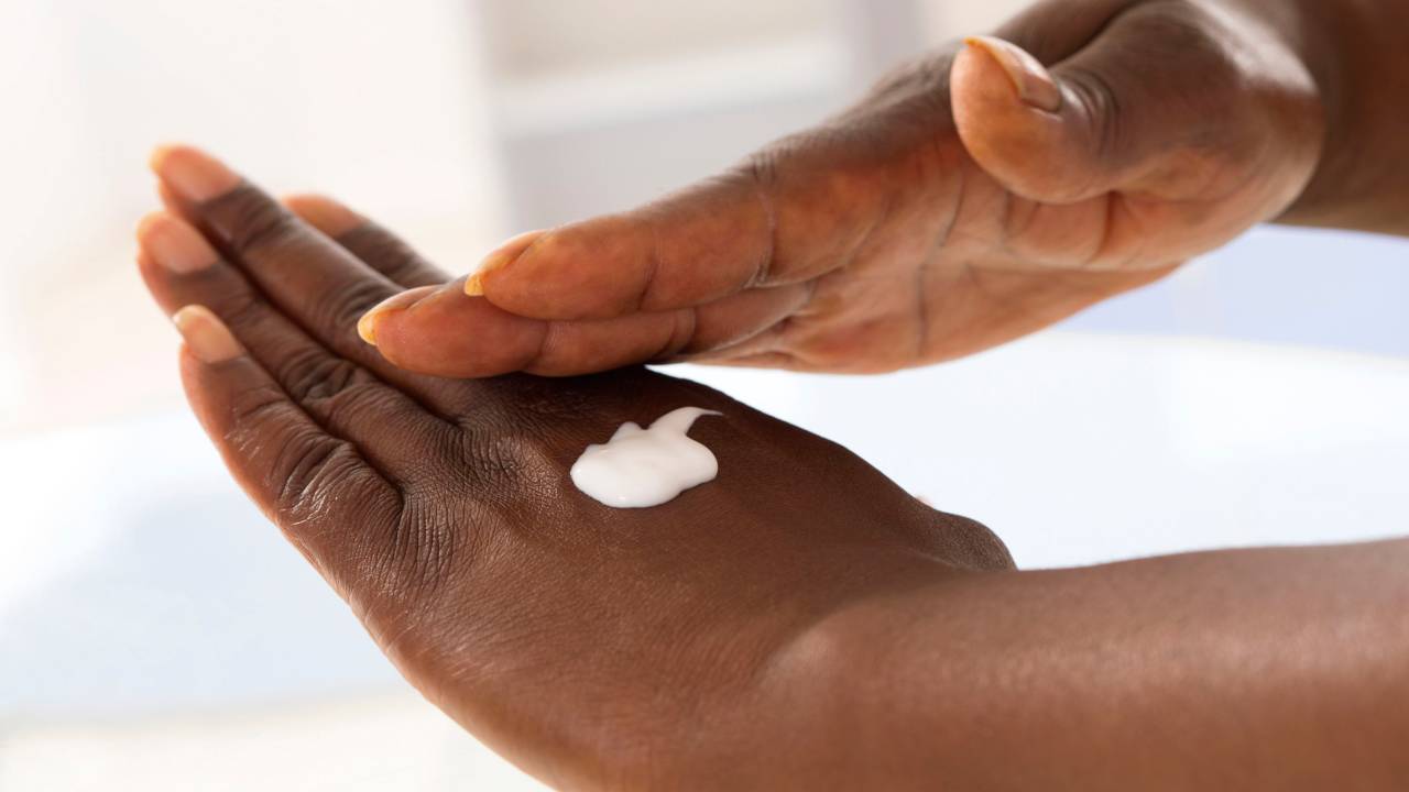 Mulher passa creme nas mãos