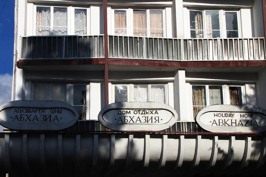 Fachada do hotel Abkhazia com placas em abkhaze, russo e inglês.