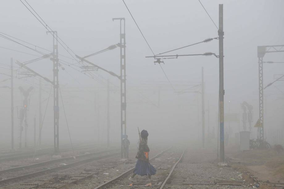 Membro tradicional do exército sikh, atravessa uma ferrovia em meio a uma densa neblina causada pela poluição nos arredores da estação de Amritsar, na Índia - 07/11/2017