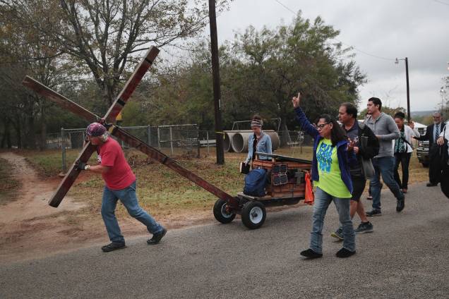 Stephen Hope carega uma cruz pela cidade seguido de outros fiéis após o culto dominical da Igreja Batista de Sutherland Springs, no Texas. A cerimônia foi realizada em uma barraca em um campo de beisebol da cidade - 12/11/2017 Stephen Hope carega uma cruz pela cidade seguido de outros fiéis após o culto dominical da Igreja Batista de Sutherland Springs, no Texas. A cerimônia foi realizada em uma barraca em um campo de beisebol da cidade - 12/11/2017
