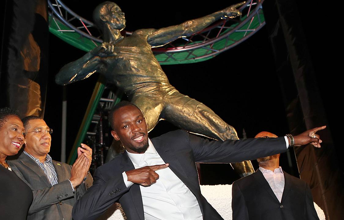Campeão olímpico, Usain Bolt, posa em frente a estátua em sua homenagem em Kingston, na Jamaica