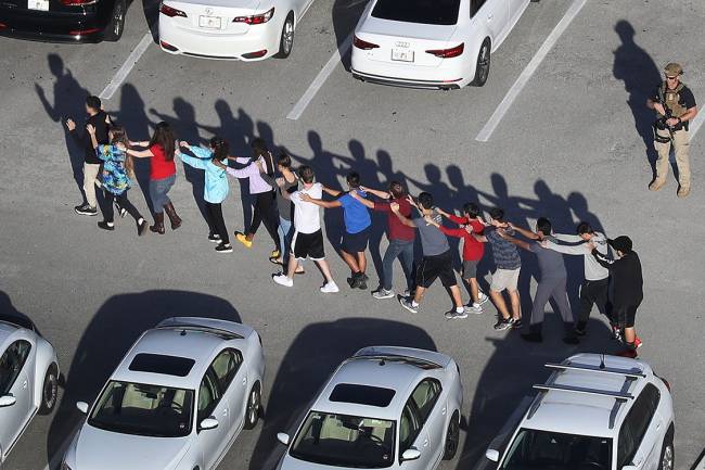 Pessoas são retiradas da escola Marjory Stoneman Douglas, após tiroteio que deixou mortos e feridos na cidade de Parkland, Flórida Pessoas são retiradas da escola Marjory Stoneman Douglas, após tiroteio que deixou mortos e feridos na cidade de Parkland, Flórida