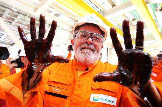 O então presidente da República, Luiz Inácio Lula da Silva, coloca as mãos no petróleo durante visita ao navio-plataforma FPSO, localizado no Campo de Tupi, litoral sul do Rio de Janeiro – 28/10/2010