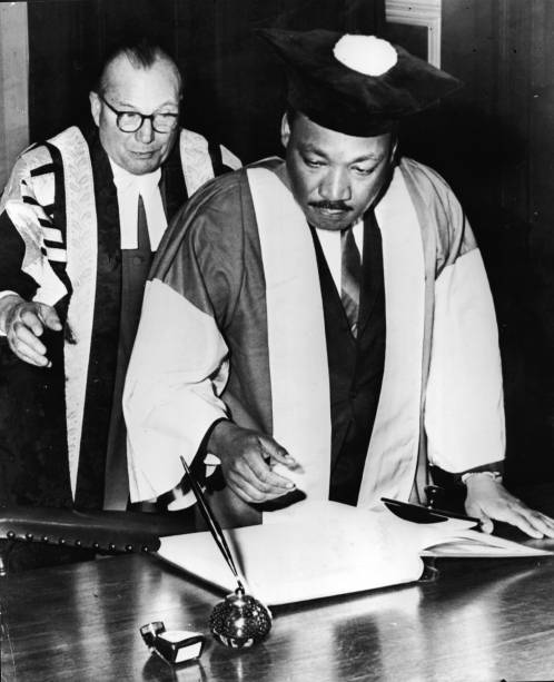 Martin Luther King, Jr., assistido pelo Dr. Charles Bousenquet, assina o curso de graduação na Universidade de Newcastle depois de receber um título honorário de Doutor em Direito Civil, na Inglaterra - 14/11/1967 Martin Luther King, Jr., assistido pelo Dr. Charles Bousenquet, assina o curso de graduação na Universidade de Newcastle depois de receber um título honorário de Doutor em Direito Civil, na Inglaterra - 14/11/1967