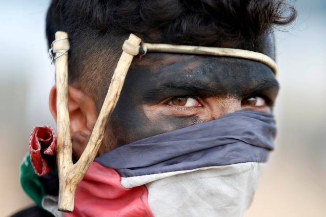 Manifestante palestino usa um estilingue durante protesto contra a mudança da embaixada dos Estados Unidos para Jerusalém e antes do 70º aniversário de Nakba, na fronteira entre Israel e Gaza, a leste da Cidade de Gaza - 14/05/2018 Manifestante palestino usa um estilingue durante protesto contra a mudança da embaixada dos Estados Unidos para Jerusalém e antes do 70º aniversário de Nakba, na fronteira entre Israel e Gaza, a leste da Cidade de Gaza - 14/05/2018