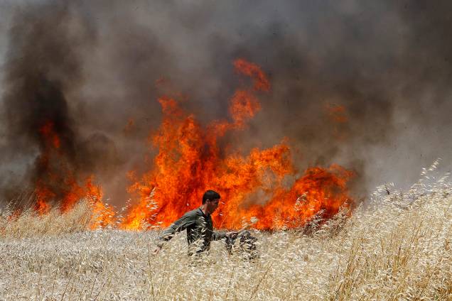 Soldado Israelense tenta apagar fogo em plantação de trigo causado por manifestantes na Faixa de Gaza - 14/05/2018 Soldado Israelense tenta apagar fogo em plantação de trigo causado por manifestantes na Faixa de Gaza - 14/05/2018