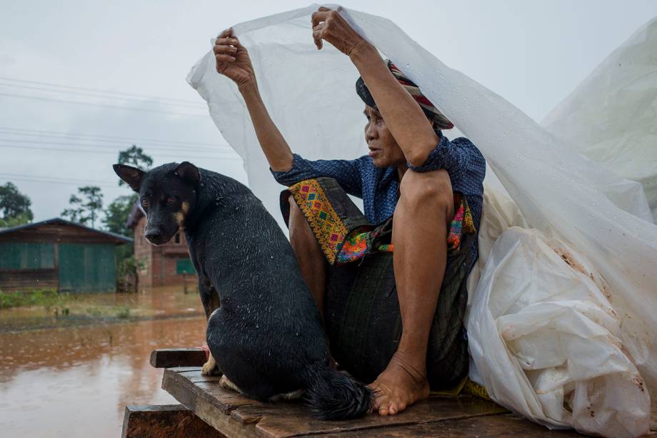 Mulher carrega seu cachorro e alguns pertences sobre uma embarcação na região alagada de Sanamxai, província de Attapeu, após uma barragem ter cedido no Laos - 26/07/2018