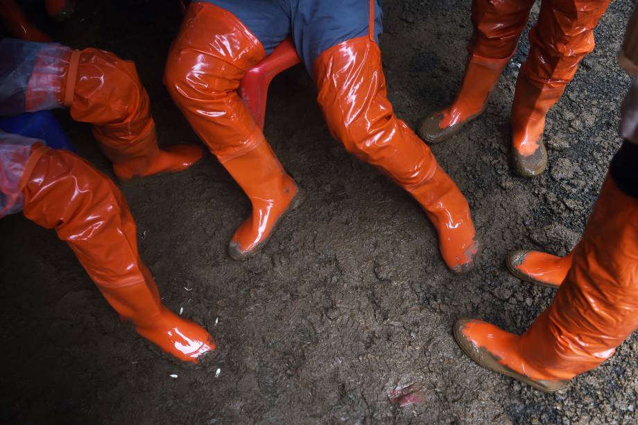 Paramédicos voluntários usam botas no chão lamacento do posto avançado na entrada da caverna de Tham Luang, durante operação de resgate de um time de futebol infantil e seu treinador presos no local - 27/06/2018