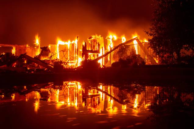 Casa em chamas reflete nas águas de uma piscina durante o incêndio Carr, que atinge a cidade de Redding, na Califórnia - 27/07/2018 Casa em chamas reflete nas águas de uma piscina durante o incêndio Carr, que atinge a cidade de Redding, na Califórnia - 27/07/2018