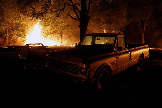 Chamas do incêndio florestal Carr queimam atrás de uma caminhonete na cidade de Redding, na Califórnia - 27/07/2018 Chamas do incêndio florestal Carr queimam atrás de uma caminhonete na cidade de Redding, na Califórnia - 27/07/2018