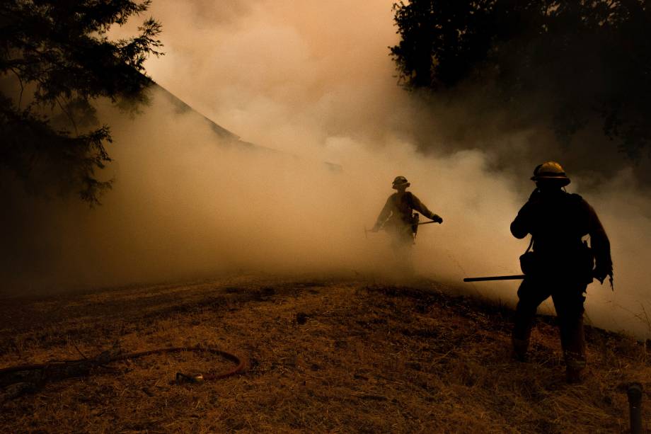 Bombeiros atravessam a fumaça enquanto as chamas se aproximam de uma casa durante o incêndio no complexo de Mendocino, em Lakeport, na Califórnia - 30/07/2018