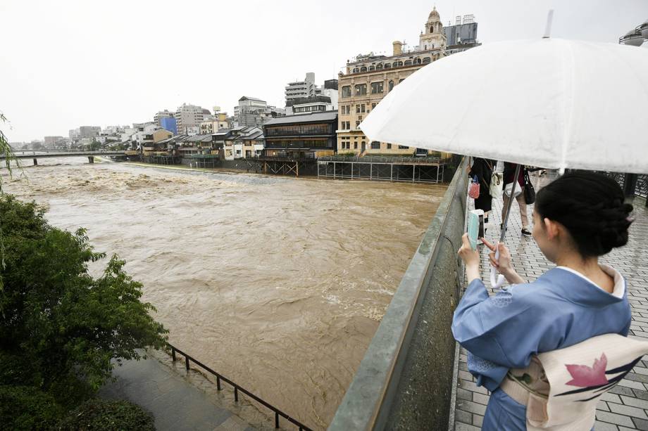 Mulher tira foto de inundação próximo do Rio Kamo, em Kyoto - 05/07/2018