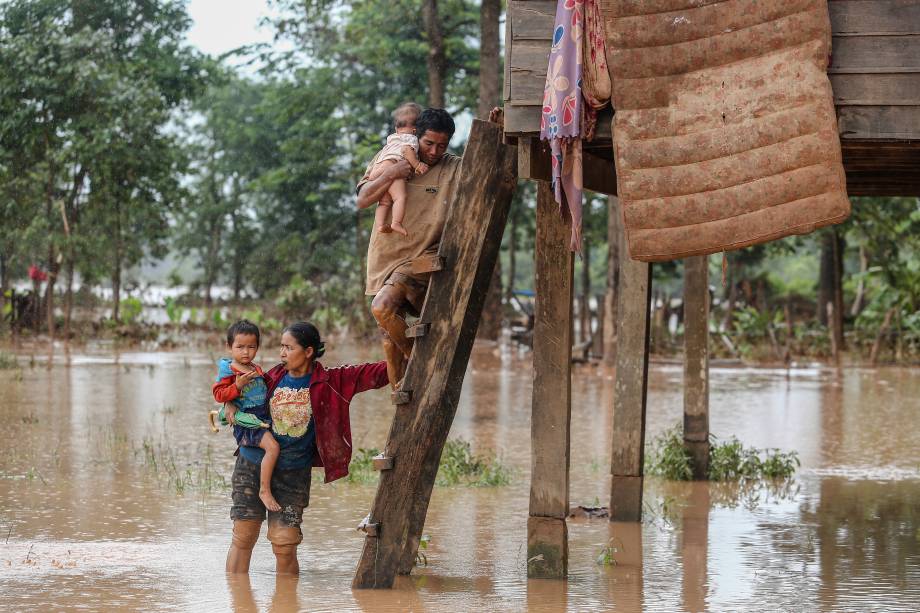 Pais carregam seus filhos após deixarem sua casa durante enchente provocada pelo rompimento da represa de Xepian-Xe Nam Noy na província de Attapeu, Laos - 26/07/2018