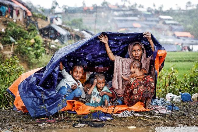 Refugiados rohingyas – Genocídio na rede Família de rohingyas protege-se da chuva, em Bangladesh: refúgio no país vizinho.