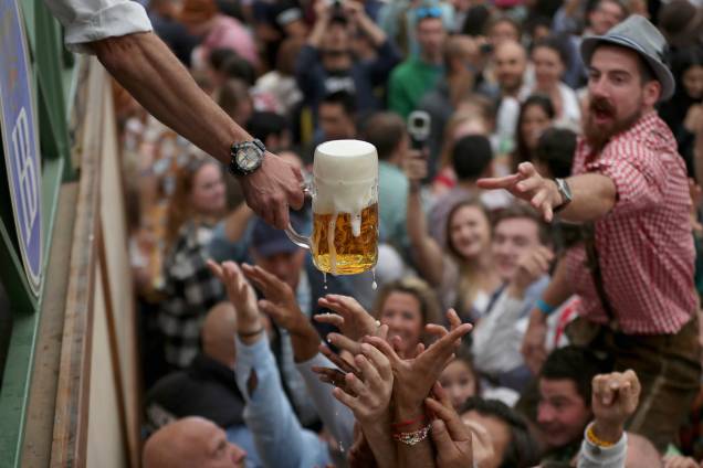 Visitantes se esforçam para alcançar uma caneca de cerveja durante a Oktoberfest de Munique, na Alemanha - 22/09/2018 Visitantes se esforçam para alcançar uma caneca de cerveja durante a Oktoberfest de Munique, na Alemanha - 22/09/2018