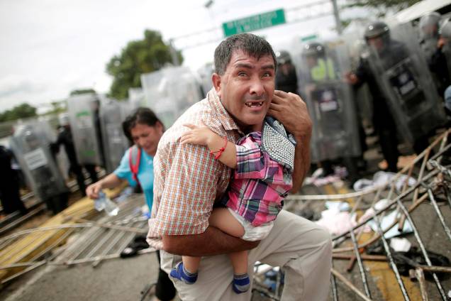 Imigrante hondurenho protege seu filho depois que outros imigrantes, parte de uma caravana que tentava chegar aos Estados Unidos, invadiram um posto fronteiriço em Ciudad Hidalgo, México - 20/10/2018 Imigrante hondurenho protege seu filho depois que outros imigrantes, parte de uma caravana que tentava chegar aos Estados Unidos, invadiram um posto fronteiriço em Ciudad Hidalgo, México - 20/10/2018