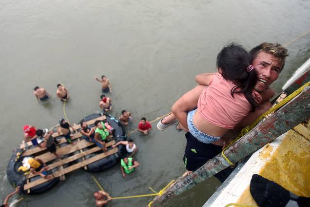 Imigrante hondurenho segura uma criança ao descer de uma ponte que liga México e Guatemala para evitar o posto fronteiriço em Ciudad Hidalgo, no México - 20/10/2018 Imigrante hondurenho segura uma criança ao descer de uma ponte que liga México e Guatemala para evitar o posto fronteiriço em Ciudad Hidalgo, no México - 20/10/2018