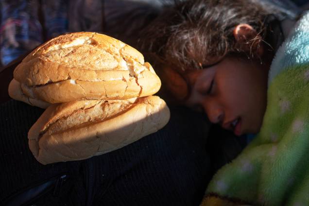 Garota dorme próxima de pão que foi doado para imigrantes hondurenhos, nos arredores da cidade mexicana de Tapachula - 22/10/2018 Garota dorme próxima de pão que foi doado para imigrantes hondurenhos, nos arredores da cidade mexicana de Tapachula - 22/10/2018