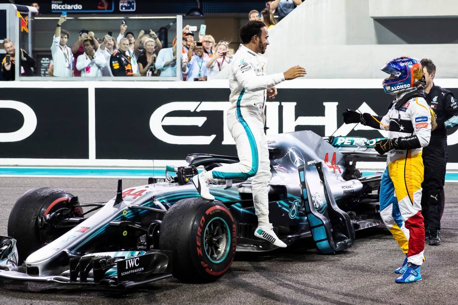 O vencedor da corrida, o britânico Lewis Hamilton da Mercedes comemora com Fernando Alonso da McLaren na despedida do piloto espanhol da F1 após o Grande Prêmio de Abu Dhabi